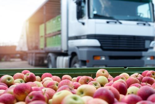 A bin of red apples in front of a white semi-truck.  